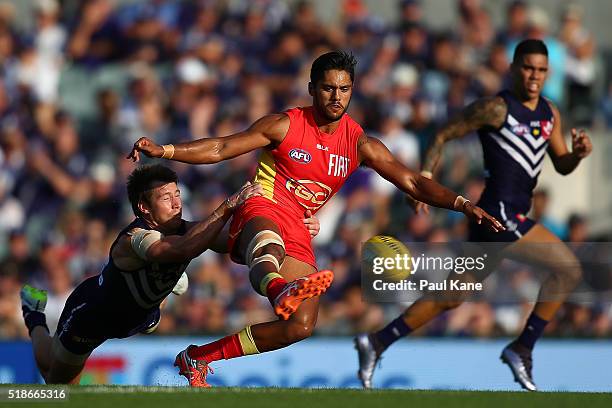 Aaron Hall of the Suns gets his kick away while being tackled by Lee Spurr of the Dockers during the round two AFL match between the Fremantle...