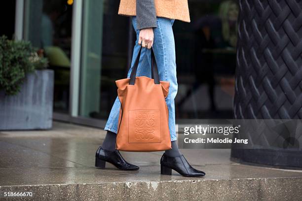 Showgoer carries an orange Loewe logo tote bag during London Fashion Week Autumn/Winter 2016/17 at the Anya Hindmarch show at Kings Cross on February...
