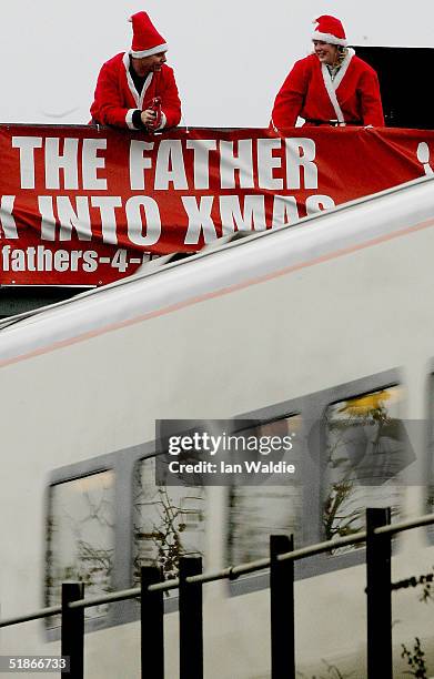 Fathers 4 Justice protestors watch a train as it passes under a signalling gantry December 16, 2004 in London, England. Fathers 4 Justice is a civil...