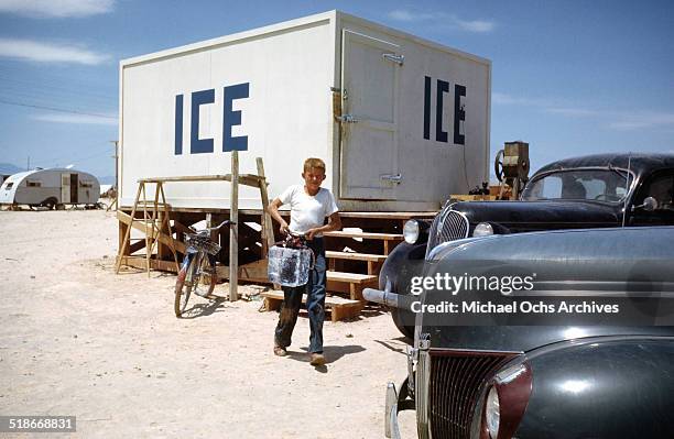 View as a boy carries a block of ice at Tent City Nevada, housing for workers and thier families at the Basic Magnesium Incorporated a Magnesium...