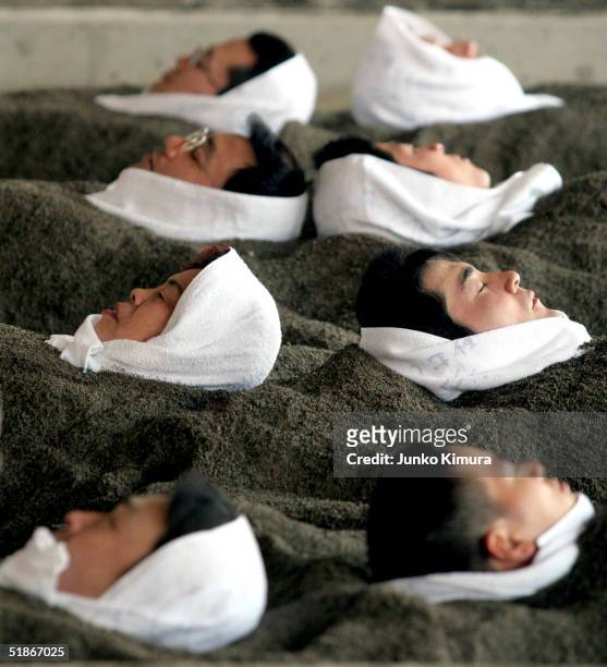 People are buried to their neck in black sand for a hot sand bath on December 16, 2004 in Ibusuki, Kagoshima Prefecture, Japan. Japanese have been...