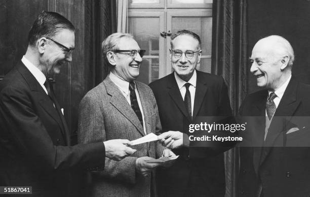 Envoy Nils Stahle hands over the cheques to the joint winners of the 1970 Nobel Prize in Medicine, in Sweden, 11th December 1970. From left to right,...