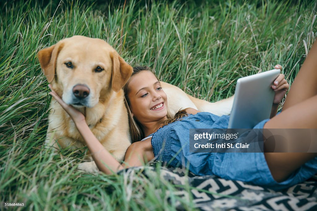 Girl, head on dog, with tablet computer