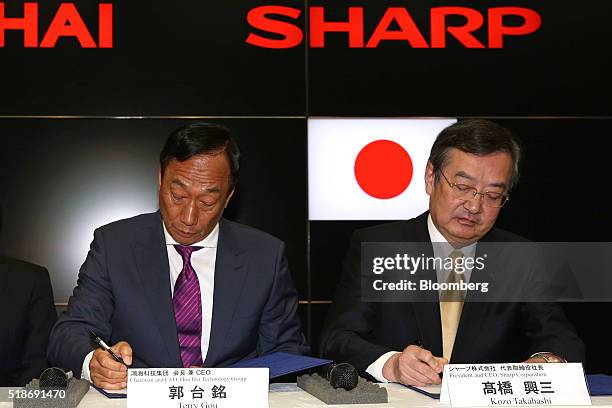 Billionaire Terry Gou, chairman of Foxconn Technology Group, and Kozo Takahashi, president of Sharp Corp., sign documents during a news conference in...