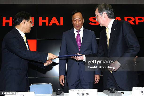 Kozo Takahashi, president of Sharp Corp., right, passes documents to Tai Jeng-wu, vice president of Foxconn Technology Group, left, as Billionaire...