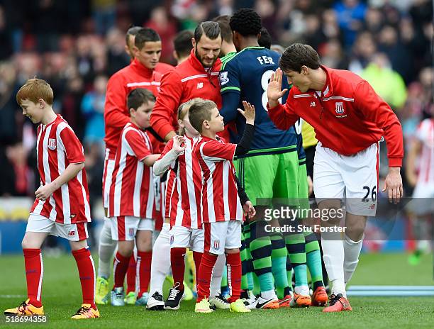 Philipp Wollscheid of Stoke City and a matchday mascot high five prior to the Barclays Premier League match between Stoke City and Swansea City at...