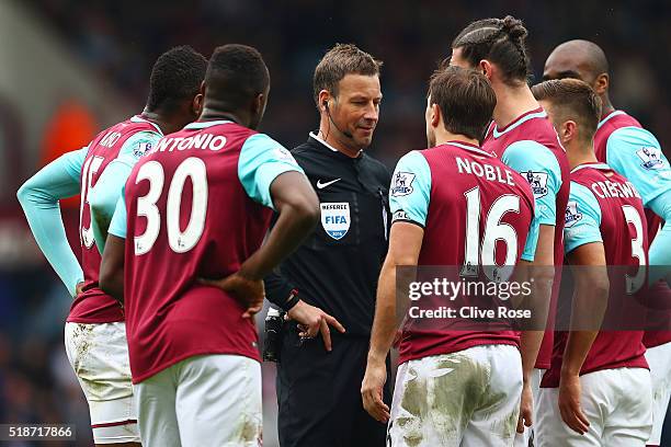 Referee Mark Clattenburg is surrounded by West Ham players after sending off Cheikhou Kouyate during the Barclays Premier League match between West...