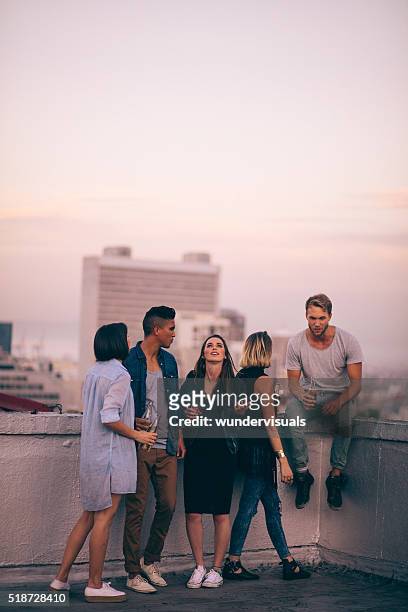 hipster style friends celebrating a summer rooftop party - engaged sunset stockfoto's en -beelden