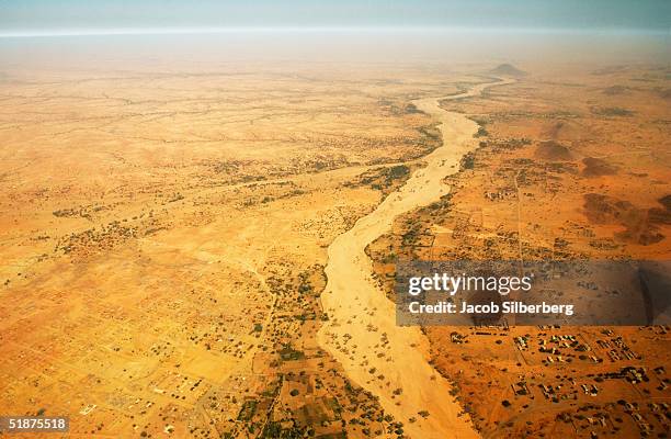 Homes and farms line the banks of a wadi, or dry river bed November 27, 2004 in Kutum, North Darfur, Sudan. During the rainy season, wadis become...