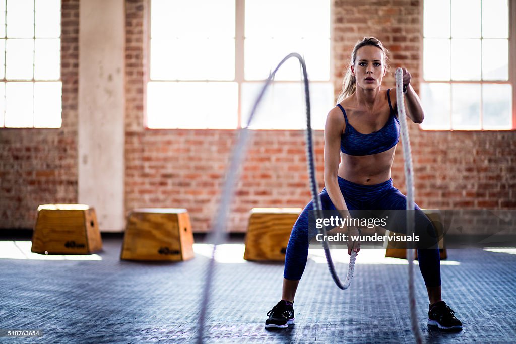 Sportliche Mädchen konzentriert sich auf fitness-training mit Seil im fitness-Center