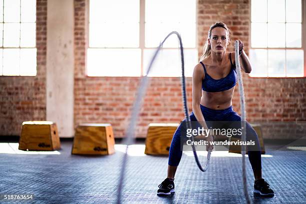 athletic girl focused on fitness training with ropes at gym - effort stock pictures, royalty-free photos & images