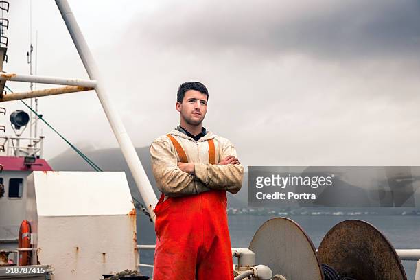 confident fisherman standing on fishing boat - pêcheur photos et images de collection