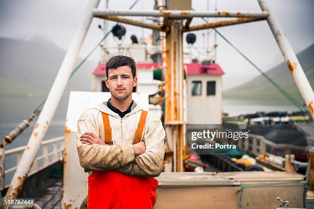 confident fisherman standing on fishing boat - bateau de pêche photos et images de collection