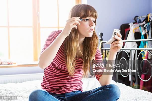 teenager putting on mascara in bedroom. - applying mascara stock pictures, royalty-free photos & images