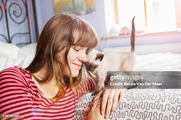 kitten gives cuddles to teenager in bedroom. - girls cuddling cat stock-fotos und bilder