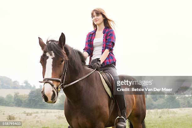 young woman horseriding in hils and fields. - sattel und zaumzeug stock-fotos und bilder