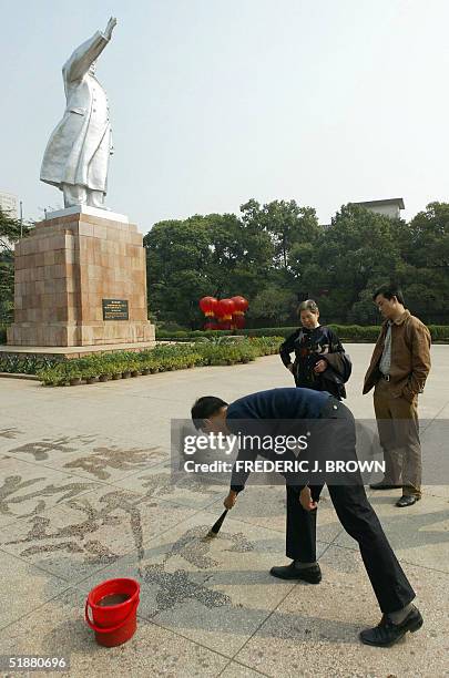 Man practices the craft of writing Chinese characters, or calligraphy, beneath a state of Communist China's former top leader Mao Zedong, 28 October...