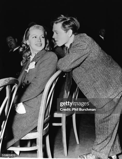 American actress Lana Turner turns around in her chair and smiles at American actor Mickey Rooney, circa 1938.