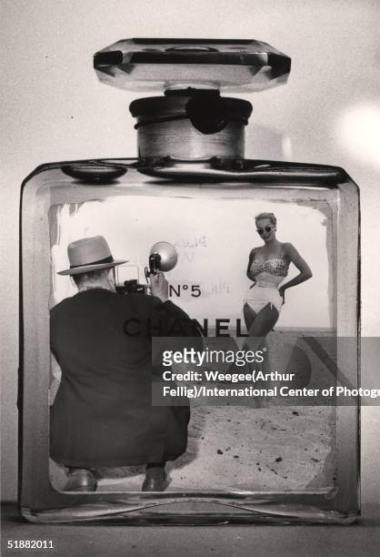 Photomontage of American photographer Weegee taking a photograph of a woman in a bathing suit inside a Chanel No. 5 cologne bottle, late 1950s.