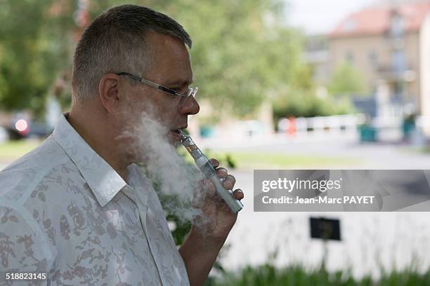 man with casual look smoking e-cigarette - jean marc payet photos et images de collection