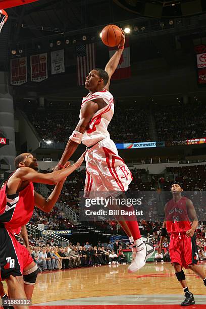 Tracy McGrady of the Houston Rockets dunks over Loren Woods of the Toronto Raptors on December 20, 2004 at the Toyota Center in Houston, Texas. NOTE...