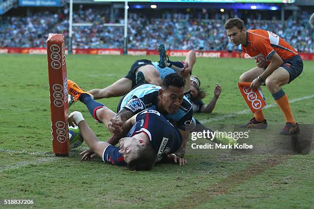 Jonah Placid of the Rebels is tackled into touch as he attempts to score in the corner by Israel Folau of the Waratahs during the round six Super...