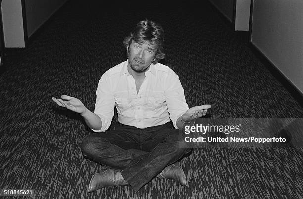 English BBC radio 1 DJ Noel Edmonds pictured sitting cross legged in an office corridor in London on 7th April 1981.