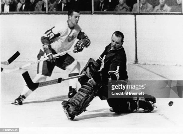 Val Fonteyne of the Detroit Red Wings watches the puck as goalie Johnny Bower of the Toronto Maple Leafs tries to make the save during the early...