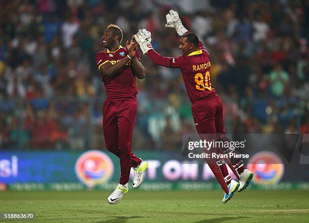 Andre Russell of the West Indies and Denesh Ramdin of the West Indies celebrate after taking the wicket of Alex Hales of England during the ICC World...