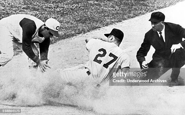 St Louis Cardinal outfielder Don Taussig stirs up a cloud of dust on an attempted steal but is called out at third by umpire Augie Donatelli as Reds...