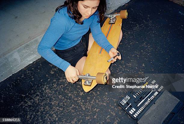 girl on driveway fixing her longboard - toledo ohio stockfoto's en -beelden