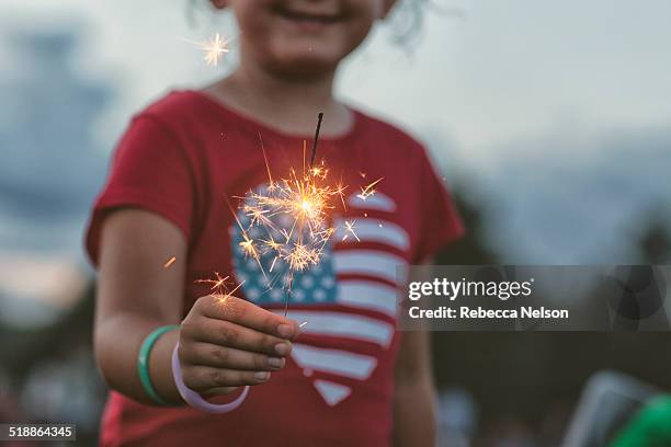 midsection of girl holding lit sparkler - día de la independencia fotografías e imágenes de stock