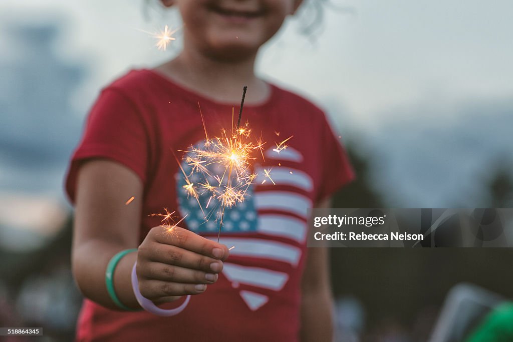 Midsection of girl holding lit sparkler