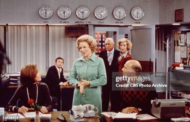 American actress Mary Tyler Moore sits at her desk as Betty White talks to her and Gavin MacLeod listens in a scene from 'The Mary Tyler Moore Show'...