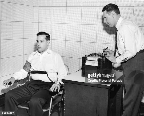 American inventor John Larson demonstrates the operation of a polygraph or 'lie detector' at Northwestern University, Evanston, Illinois, 1930s. Such...