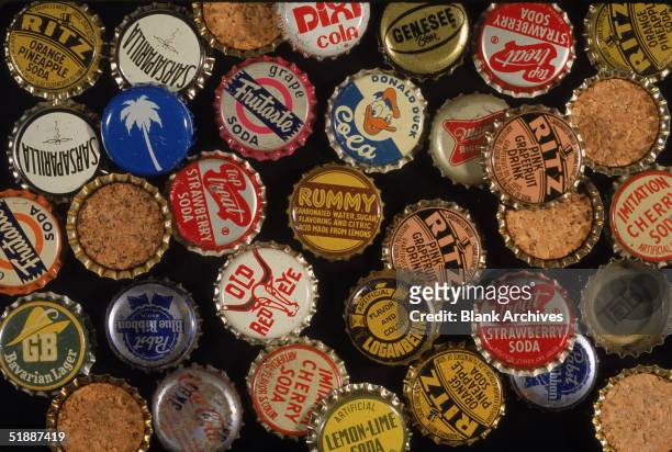 An assortment of American soda, juice, and beer bottle caps mostly from the 1950s and early 1960s. Some are flipped-over to show cork backing.