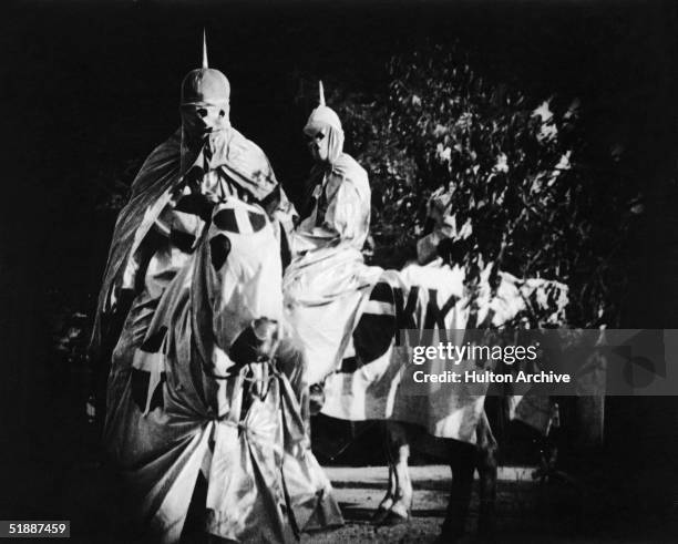 Actors costumed in the full regalia of the Ku Klux Klan ride on horses at night in a still from the first feature-length film 'The Birth of a...