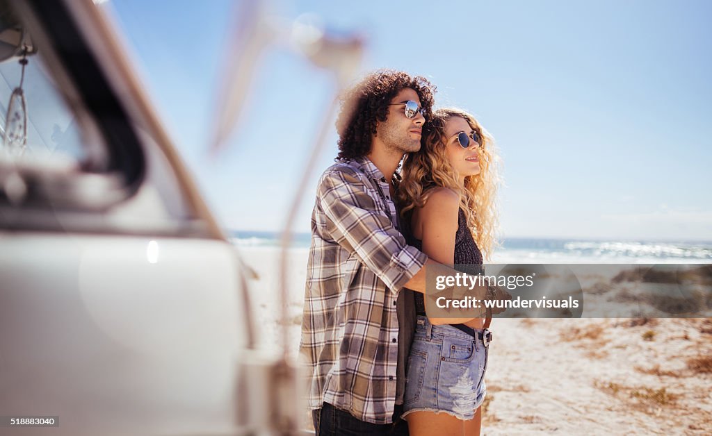 Trendy Hipster Couple Hugging in front of a Sandy Beach