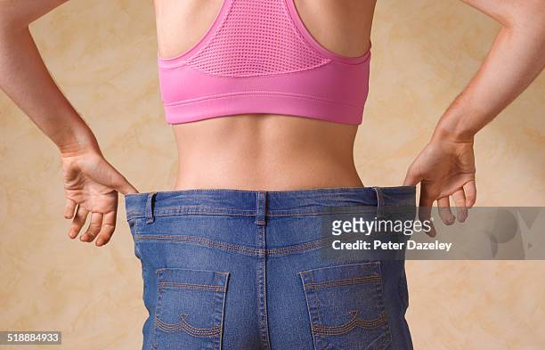dieting woman in jeans too large - delgado fotografías e imágenes de stock