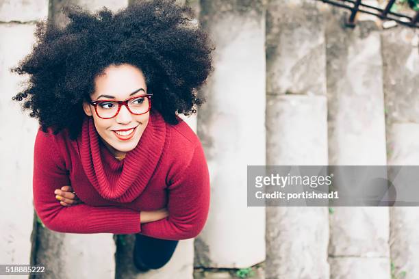 portrait of smiling young woman standing on stairs - houding stockfoto's en -beelden