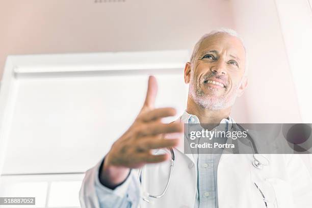 happy male doctor offering handshake in clinic - hello sunshine stock pictures, royalty-free photos & images