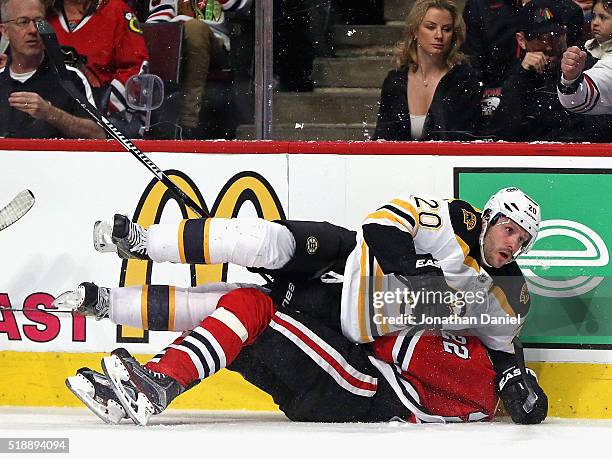 Lee Stempniak of the Boston Bruins lands on top of Marcus Kruger of the Chicago Blackhawks after a collison along the boards at the United Center on...