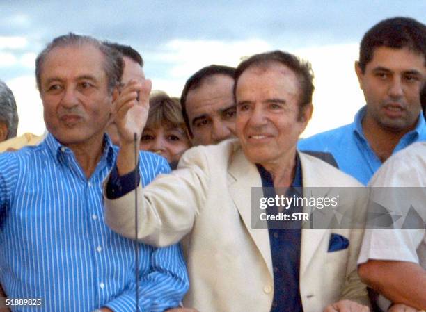 Former Argentine President Carlos Menem waves surrounded by supporters upon arriving 22 December, 2004 at the airport of La Rioja, northwestern...