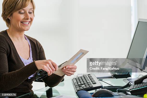 middle-aged woman looking at bills at computer - letter opener stock pictures, royalty-free photos & images