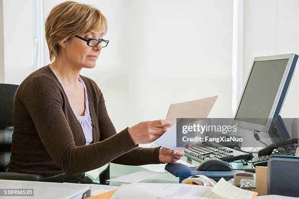 middle-aged woman looking at bills at computer - transparent business card stock pictures, royalty-free photos & images