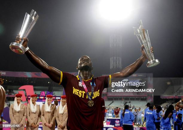 West Indies captain Darren Sammy poses with a pair of trophies as he celebrates after victory in the World T20 cricket tournament final match between...