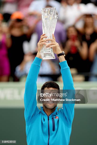 Novak Djokovic of Serbia celebrates with the Butch Buchholz trophy after defeating Kei Nishikori of Japan during the final on Day 14 of the Miami...