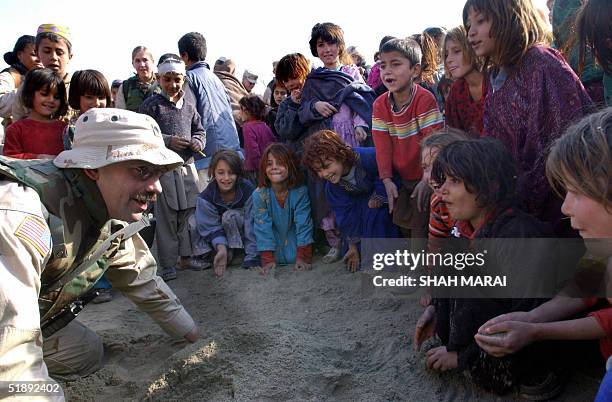 Soldier plays with Afghan children after distributing Christmas gifts and supplies during a humanitarian operation dubbed 'Operation Goodwill' in the...