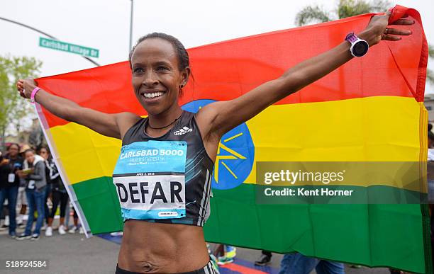 Meseret Defar of Ethiopia poses her nation's flag at the finish line after finishing first in the Elite field at the Carlsbad 5000 on April 3, 2016...