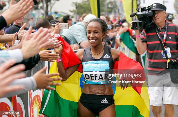 Meseret Defar of Ethiopia greets fans wrapped in her nation's flag after finishing first in the Elite field at the Carlsbad 5000 on April 3, 2016 in...